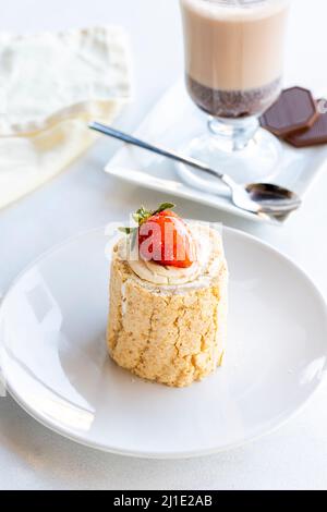 Strawberry log cake on a white background. With hot chocolate on the side. close up Stock Photo