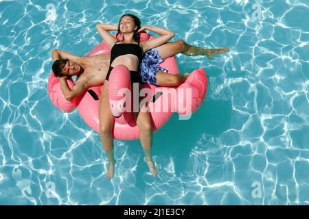 29.07.2021, Italy, Viterbo, Bolsena - young couple lying in a swimming pool on an air mattress. 00S210729D202CAROEX.JPG [MODEL RELEASE: NO, PROPERTY R Stock Photo