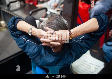 24.02.2019, Singapore, , Singapore - Close-up shows the tangled hands behind the head of an elderly man in Chinatown wearing a wristwatch, bracelet an Stock Photo