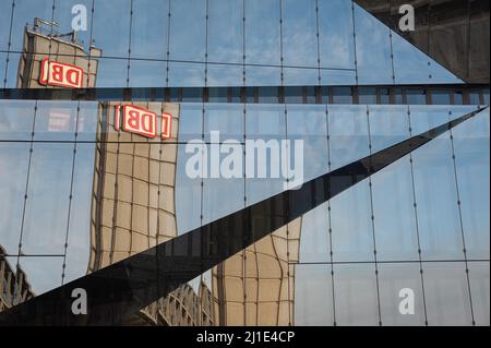 22.01.2022, Germany, , Berlin - The tower of Berlin's main train station with the DB logo is reflected in the futuristic glass facade of the new 3XN C Stock Photo