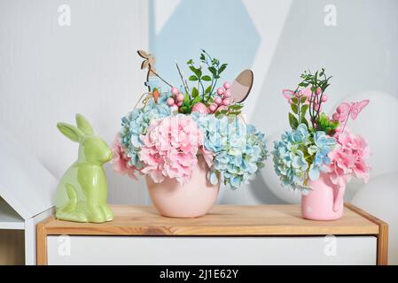 Easter decor with a hare and flowers on a wooden shelf in the interior Stock Photo