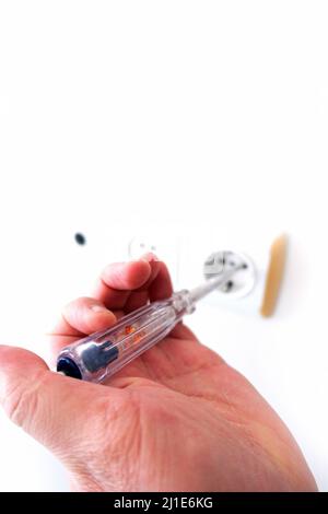an electrician measuring the electricity in the socket with an electric control pen, Stock Photo