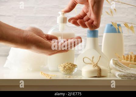 Applying oatmeal soap on hands and shower products around on white table. Front view. Horizontal composition. Stock Photo