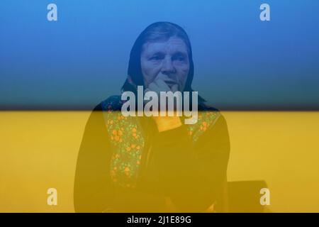 Ukraine senior farmer. Defocus portrait of 60s russian grandmother senior old woman seating indoors. Old women in shawl. Sad thinking person close-up. Stock Photo