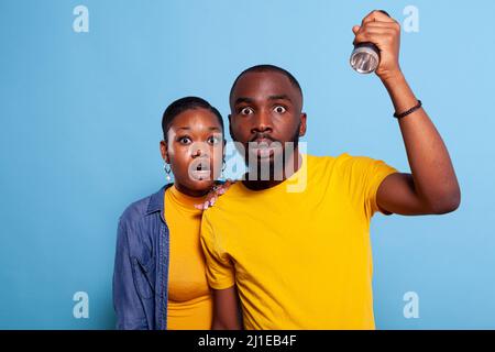 Terrified people using flashlight to check problem source, having anxious facial expression. Frightened and distraught couple looking for fear sound to avoid shock. Afraid girlfriend and boyfriend Stock Photo