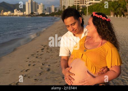 Young happy couple (pregnant woman) on beach Stock Photo