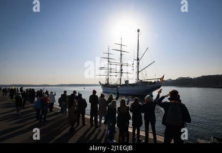 Kiel, Germany. 25th Mar, 2022. Relatives and friends greet the 'Gorch Fock' as it docks at the pier at the Kiel-Wik naval base. The navy's sail training ship returned to its home port after a four-month training voyage and moors backwards at the Gorch Fock pier. Credit: Christian Charisius/dpa/Alamy Live News Stock Photo