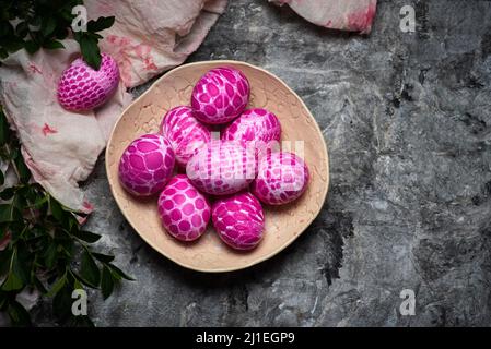 Lace pattern painted pink Easter eggs on a plate on gray background with copy space top view. Easter holiday background Stock Photo