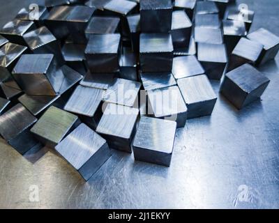 pile of small machined shiny steel cubes on metal surface Stock Photo