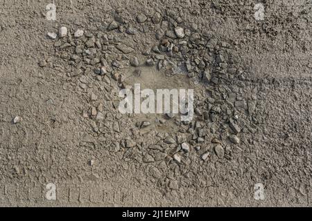 crumbling dirt road without asphalt pavement, made of clay and dirt with rubble, with pits and potholes filled with water, puddles wet after rain Stock Photo