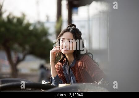 Beautiful young Chinese lady enjoying afternoon tea in sidewalk cafe - stock photo Stock Photo