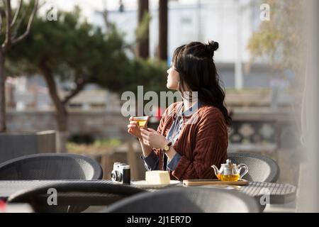 Chinese college student enjoying afternoon tea in sidewalk cafe - stock photo Stock Photo