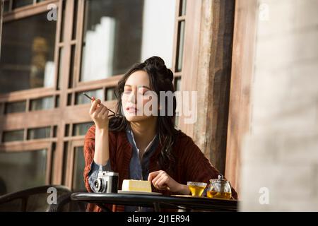 Chinese college student enjoying afternoon tea in sidewalk cafe - stock photo Stock Photo