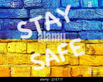 slogan Stay Safe on Ukrainian flag painted on brick wall Stock Photo