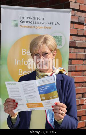 Jena, Germany. 25th Mar, 2022. Astrid Heßmer, Managing Director of the Thuringian Cancer Society, stands in front of the office with an advertising flyer. People from Ukraine who have fled the war in their home country and are suffering from cancer are receiving medical help in Thuringia. The Thuringian Cancer Society has launched an aid campaign to refer Ukrainian patients to hospitals and doctors in private practice in the Free State for treatment. Credit: Bodo Schackow/dpa-Zentralbild/dpa/Alamy Live News Stock Photo