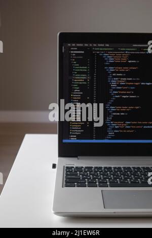 Opened laptop with code on the screen on the table Stock Photo