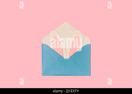 Paper rabbit ears in a blue envelope on a pink background with copy space Stock Photo