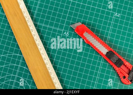 A wooden ruler and a cutter knife on a green cutting mat Stock Photo