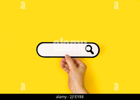Woman hand holding a blank search bar on a yellow background Stock Photo