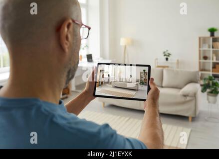 Man who's going to sell his house or apartment takes a photo of the interior on a tablet Stock Photo