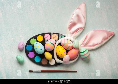 Happy Easter. Colored easter painted eggs with watercolors, brush and rabbit ears on a blue table Stock Photo