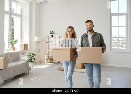 Happy young couple who've moved in a new house carrying some boxes and unpacking stuff Stock Photo