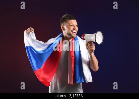 Handsome man with flag of Russia and megaphone on dark background Stock Photo