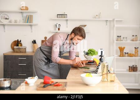 Young man making notes while cooking in kitchen Stock Photo