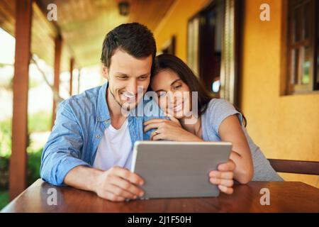 Browsing time is bonding time. Shot of a young couple using a digital tablet together outdoors. Stock Photo