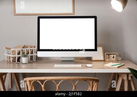 Comfortable workplace with modern computer near grey wall Stock Photo