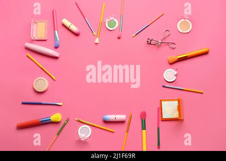 Frame made of makeup brushes and cosmetic products on pink background Stock Photo