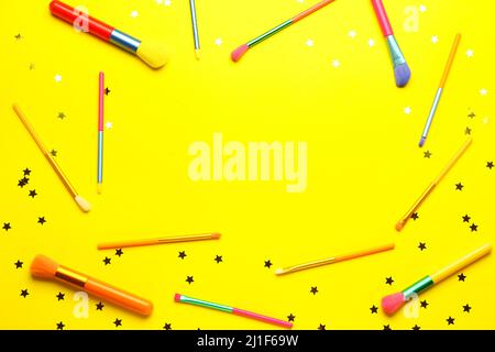 Frame made of colorful makeup brushes on yellow background Stock Photo