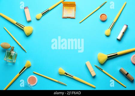 Frame made of makeup brushes and cosmetic products on blue background Stock Photo