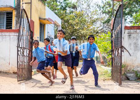 Children running out from school by opening gate after the bell - concept of education, freedom, happiness, enjoyment and childhood growth. Stock Photo