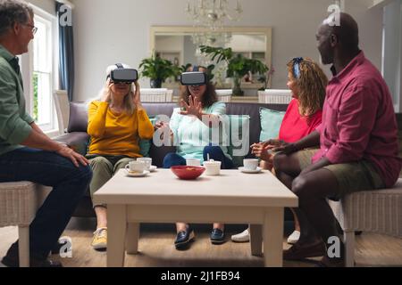Multiracial senior woman and men with friends using vr headsets at home Stock Photo
