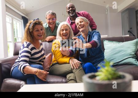 Happy multiracial senior male and female friends taking selfie through smart phone at home Stock Photo