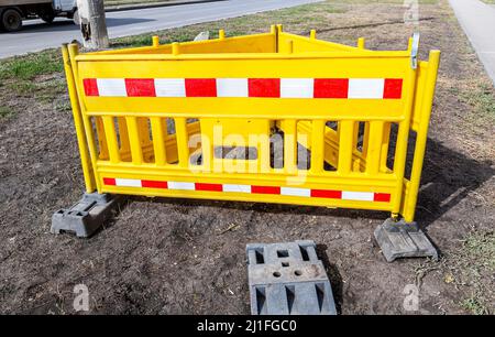 Yellow plastic fence with red and white strips at the city. Road works traffic sign at the city street Stock Photo