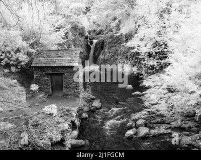 A black and white infrared image of The Grot summer house and Rydal Falls at Rydal Hall. Lake District National Park, Cumbria, England. Stock Photo