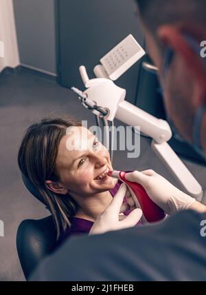 Dentist examine the colour of teeth with digital shade guide teeth color comparator Stock Photo