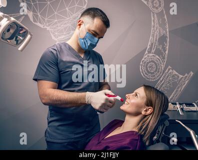 Dentist examine the colour of teeth with digital shade guide teeth color comparator Stock Photo