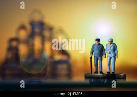 Miniature people old couple walking with a cane glass chess sunset background. Concept of retirement pension Stock Photo