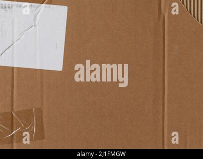 Worn cardboard texture with clear tape,  white sticker and torn part Stock Photo