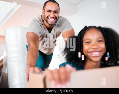 Theres plenty of room for fun here. Shot of a man pushing his daughter around in a cardboard box in their new home. Stock Photo