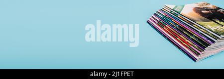 collection of colorful magazines stacked isolated on blue with copy space, banner Stock Photo