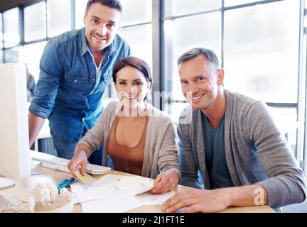 Organizing the team. Shot of three coworkers going through paperwork together. Stock Photo