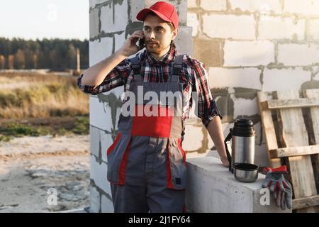Bricklayer talking by smartphone on the construction site Stock Photo