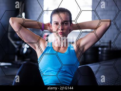 Hexagonal shapes pattern design against portrait of caucasian fit woman working out at the gym Stock Photo