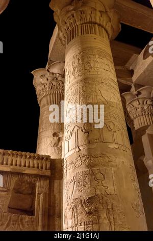 Carved columns, including a depiction of the goddess Nekhbet, at the Temple of Kom Ombo, in Aswan, at night Stock Photo