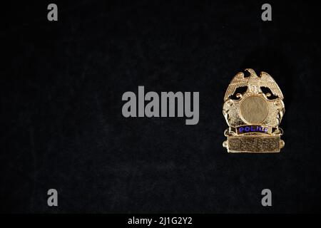 a nondescript gold police badge on a black background ith copy space Stock Photo
