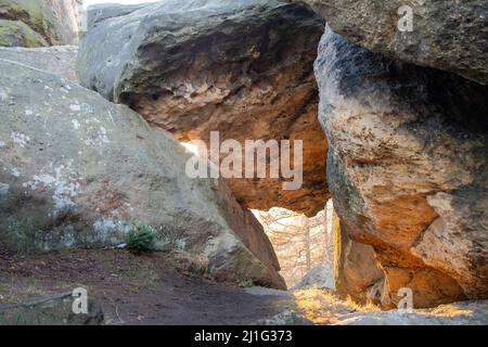 sun shining through a hole between two huge sandstone rocks Stock Photo